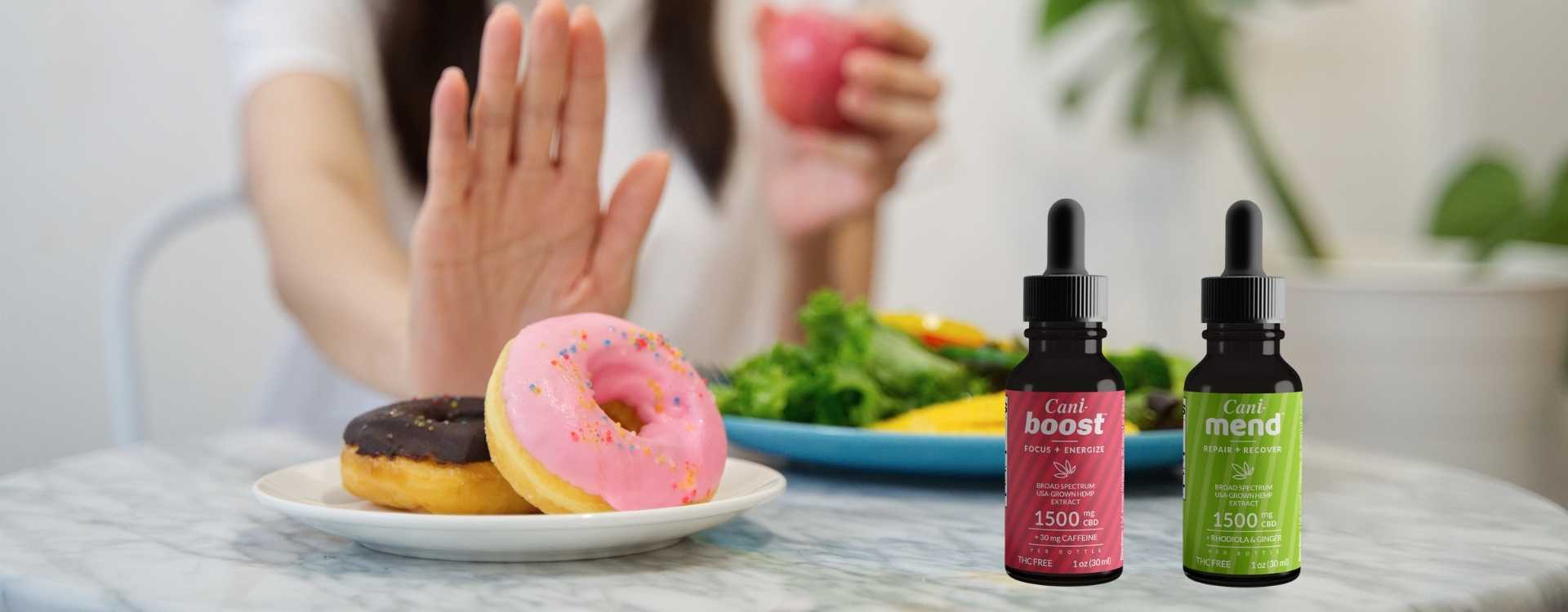 Two CBD oil tinctures between a healthy salad and two donuts